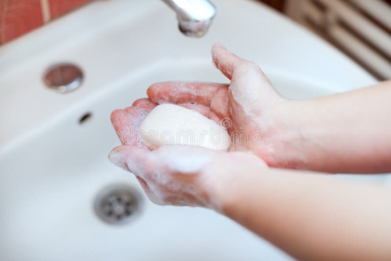 Mani insaponate che tengono sapone per il lavaggio della mano