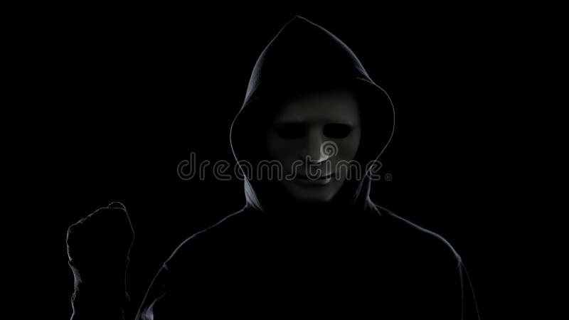 Maniac in white mask and hoodie showing fist, isolated on black background royalty free stock image Maniac in white mask and hoodie showing fist, isolated on black background royalty free stock image