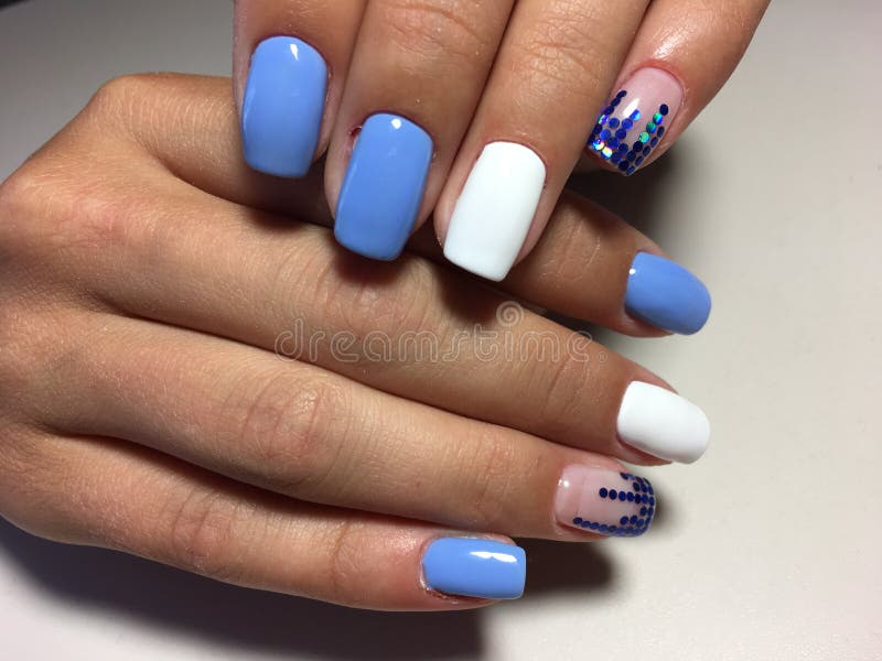 manicura azul de moda con el diseño blanco y los empeños azules fotografía de archivo manicura azul de moda con el diseño blanco y los empeños azules fotografía de archivo