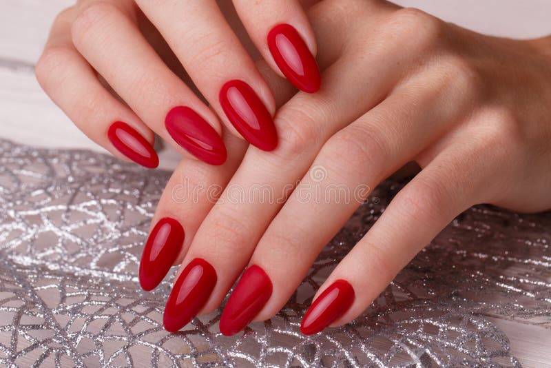Manicura roja festiva brillante en las manos femeninas Diseño de los clavos