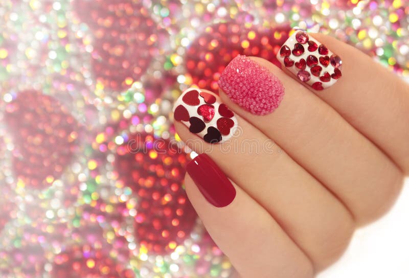 Manicure with rhinestones in the shape of hearts and pink balls on white and red nail Polish on a brilliant background. Manicure with rhinestones in the shape of hearts and pink balls on white and red nail Polish on a brilliant background.