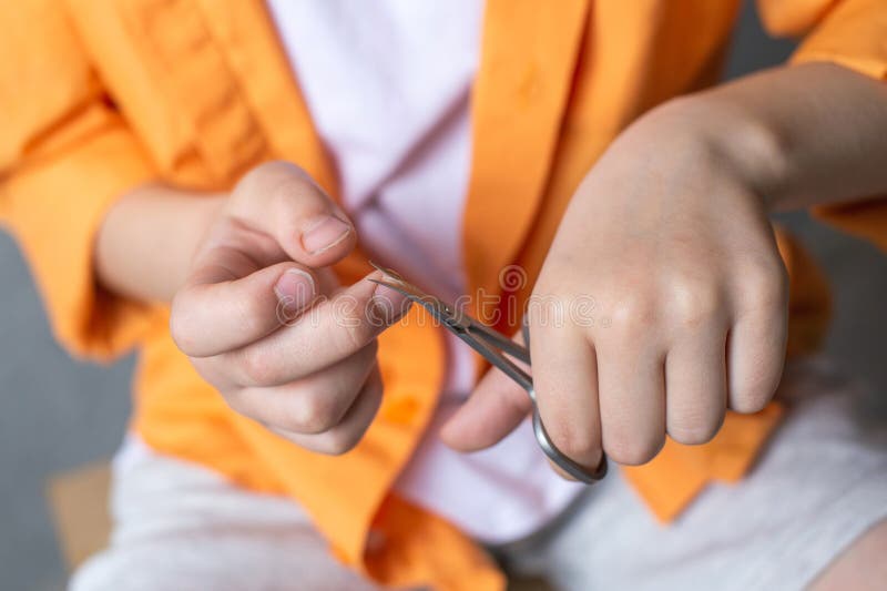 Manicure Scissors in the Hands of a Child Cut Nails. Boy Cutting His