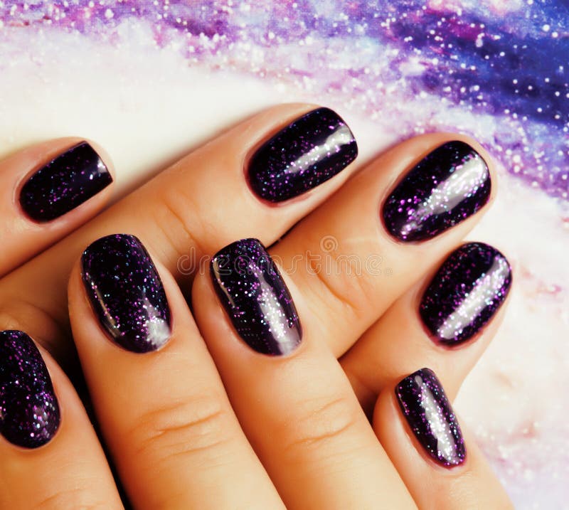 Manicure stylish concept: woman fingers with nails purple glitter on nails like cosmos, universe background