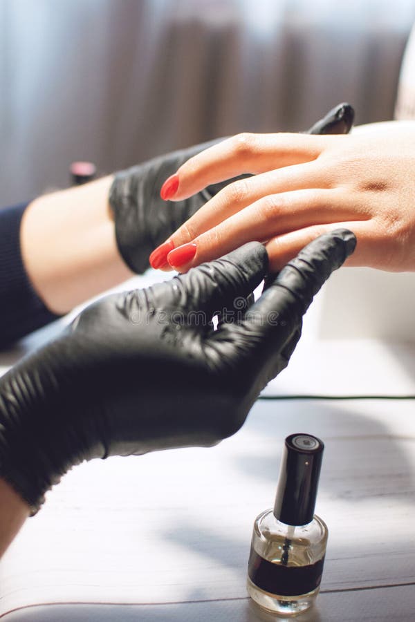 Manicure'u specjalista w czarnych r?kawiczkach dba o r?ka gwo?dziach Manicurzysta farb gwo?dzie z czerwonym gwo?dzia po?yskiem Ma obrazy royalty free Manicure'u specjalista w czarnych r?kawiczkach dba o r?ka gwo?dziach Manicurzysta farb gwo?dzie z czerwonym gwo?dzia po?yskiem Ma obrazy royalty free