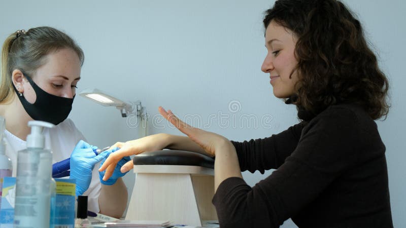 Manicurist in a beauty salon polishes his nails with a cutter. The client evaluates the work done, closely follows the royalty free stock photos Manicurist in a beauty salon polishes his nails with a cutter. The client evaluates the work done, closely follows the royalty free stock photos