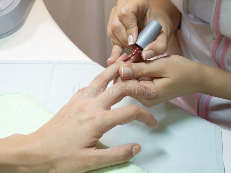 Manicurist putting red nail polish