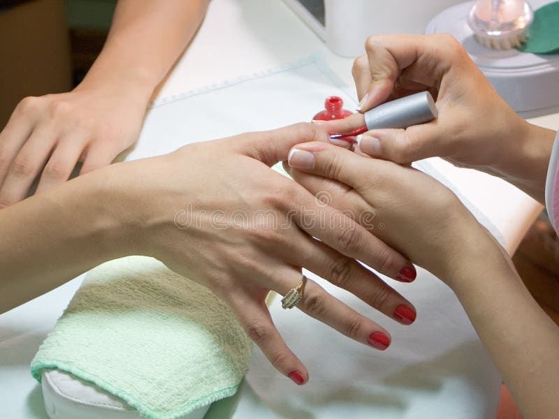 Manicurist putting red nail polish