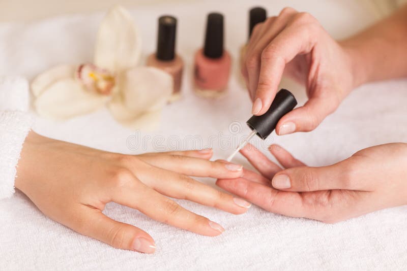 Manicuro bonito da menina que faz o tratamento de mãos para a mulher no salão de beleza imagem de stock Manicuro bonito da menina que faz o tratamento de mãos para a mulher no salão de beleza imagem de stock