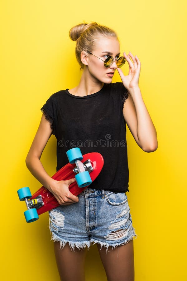 Manier gelukkig glimlachend hipster koel meisje in zonnebril met skateboard die pret hebben in openlucht tegen de gele achtergron royalty-vrije stock afbeeldingen Manier gelukkig glimlachend hipster koel meisje in zonnebril met skateboard die pret hebben in openlucht tegen de gele achtergron royalty-vrije stock afbeeldingen