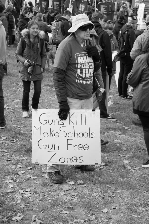 Woman holds sign at the March For Our Lives rally in Columbus, OH. 2018 Signs state `Guns Kill Make Schools Gun Free Zones.`. Woman holds sign at the March For Our Lives rally in Columbus, OH. 2018 Signs state `Guns Kill Make Schools Gun Free Zones.`