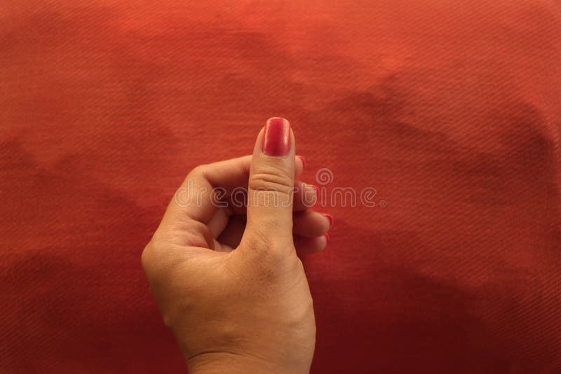 Manikürte orange Nagellack-Hand, die etwas auf zusammenpassendem Kissen hält stockbild Manikürte orange Nagellack-Hand, die etwas auf zusammenpassendem Kissen hält stockbild