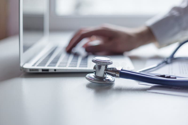 Manipulera arbete med bärbar datordatoren i medicinskt workspacekontor Fokus på stetoskopet arkivbild