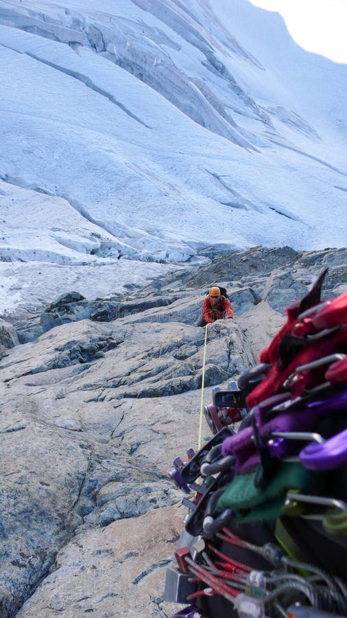 Manlig bergsbestigare på en utsatt klättringrutt som är hög ovanför en glaciär royaltyfria bilder Manlig bergsbestigare på en utsatt klättringrutt som är hög ovanför en glaciär royaltyfria bilder
