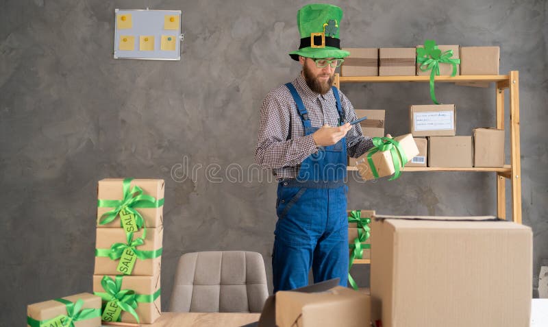 Manlig butikssäljare i leprechaun som äger småföretag som har smartphone med hjälp av mobil appskanning arkivfoton
