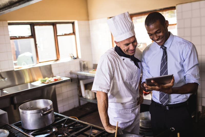 Manlig chef och kock som använder den digitala minnestavlan i kök arkivbild Manlig chef och kock som använder den digitala minnestavlan i kök arkivbild