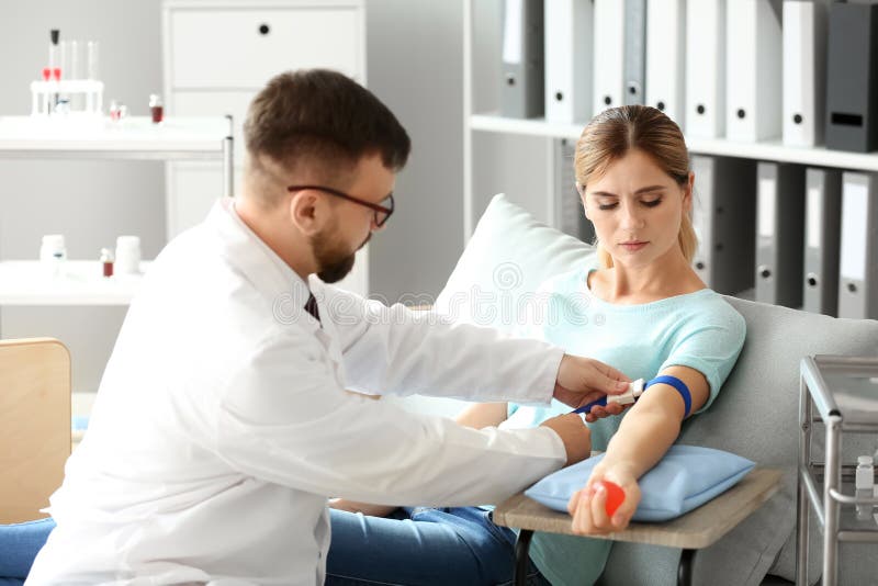 Manlig doktor som förbereder den kvinnliga givaren för blodtransfusion i sjukhus royaltyfri fotografi Manlig doktor som förbereder den kvinnliga givaren för blodtransfusion i sjukhus royaltyfri fotografi