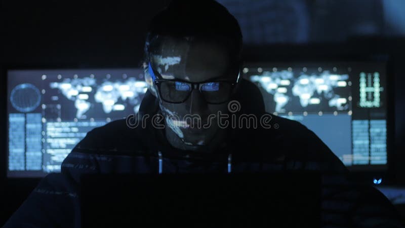 Manlig en hackerprogrammerare som arbetar på datoren, medan blåa kodtecken reflekterar på hans framsida i cybersäkerhetsmitt