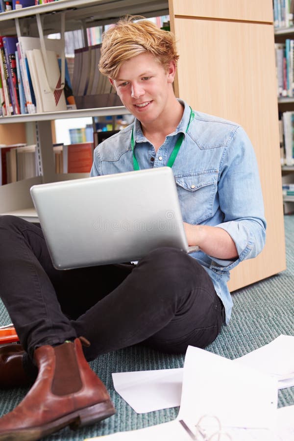 Manlig högskolestudent Studying In Library med bärbara datorn arkivbilder Manlig högskolestudent Studying In Library med bärbara datorn arkivbilder