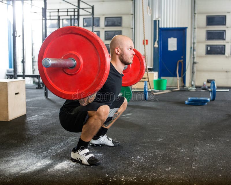 Manlig idrottsman nenLifting Barbell At idrottshall royaltyfria bilder