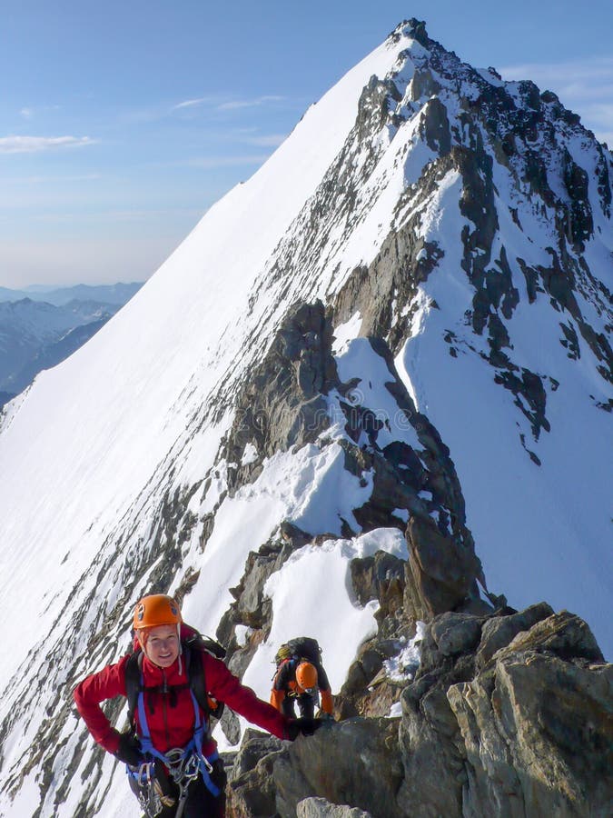 Manlig och kvinnlig bergsbestigare på en utsatt stenig toppmötekant på deras väg till ett högt alpint bergmaximum royaltyfri foto Manlig och kvinnlig bergsbestigare på en utsatt stenig toppmötekant på deras väg till ett högt alpint bergmaximum royaltyfri foto