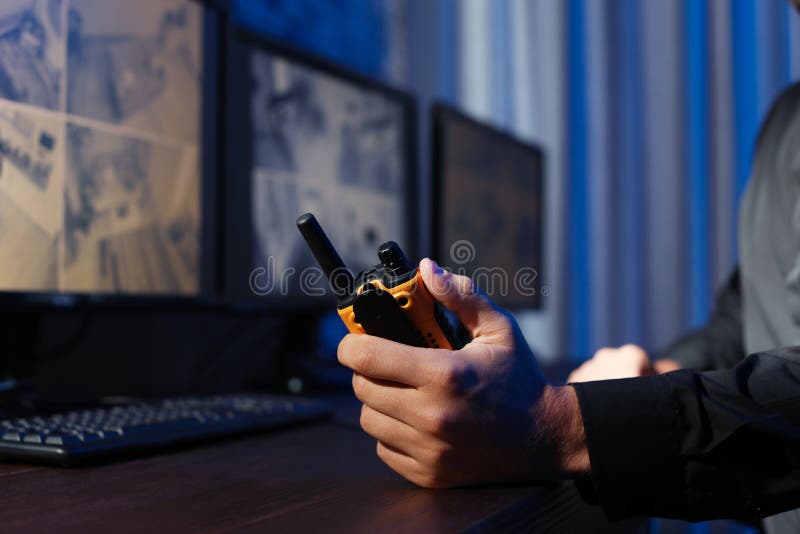 Manlig ordningsvakt med den bärbara sändaren som inomhus övervakar moderna CCTV-kameror royaltyfri bild Manlig ordningsvakt med den bärbara sändaren som inomhus övervakar moderna CCTV-kameror royaltyfri bild