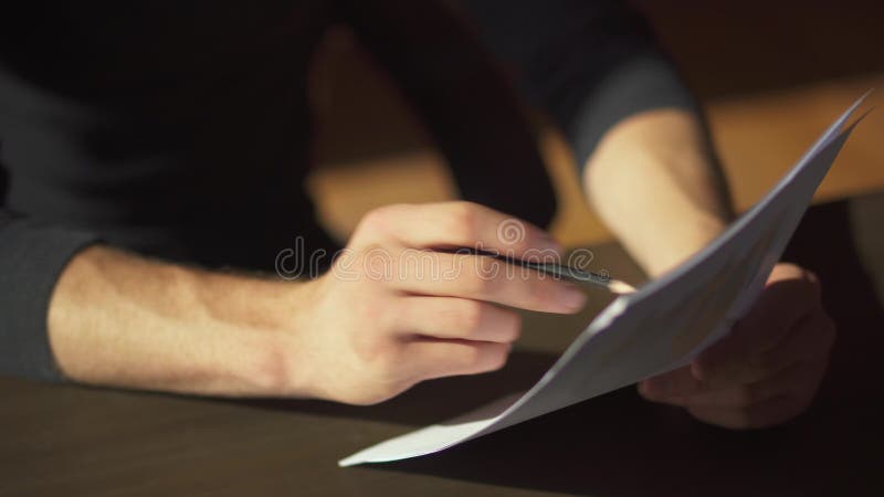 Manliga händer som gör skrivbordsarbete med att skriva rättelser i dokument, stänger sig upp En affärsman studerar diagram och gö