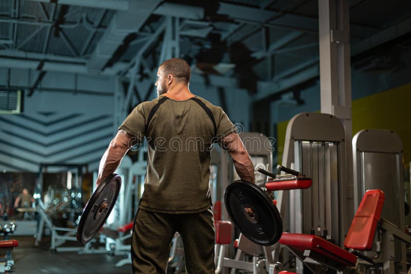 Manliga idrottsutövare som utför viktutbildning i en modern gym-miljö under kvällsworkout med fokus på kraftbyggande arkivfoton