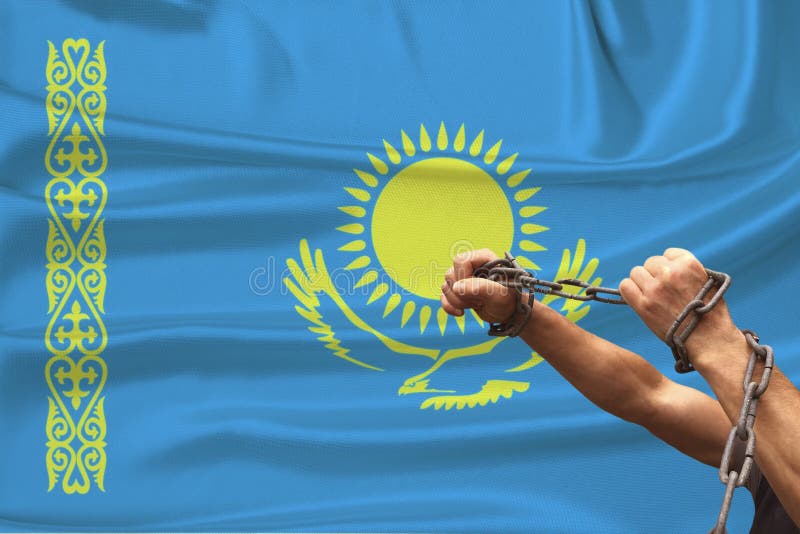 Manliga muskelhänder hos en fånge i järnkedjor mot bakgrund av den kazakstanska flaggstatens nationalflagga, begrepp arkivfoton Manliga muskelhänder hos en fånge i järnkedjor mot bakgrund av den kazakstanska flaggstatens nationalflagga, begrepp arkivfoton