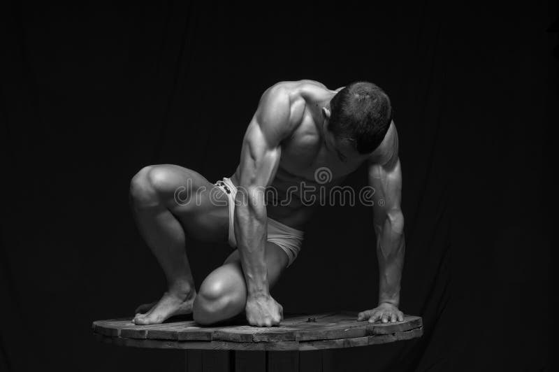 A muscular male model posing on the ground. A muscular male model posing on the ground.