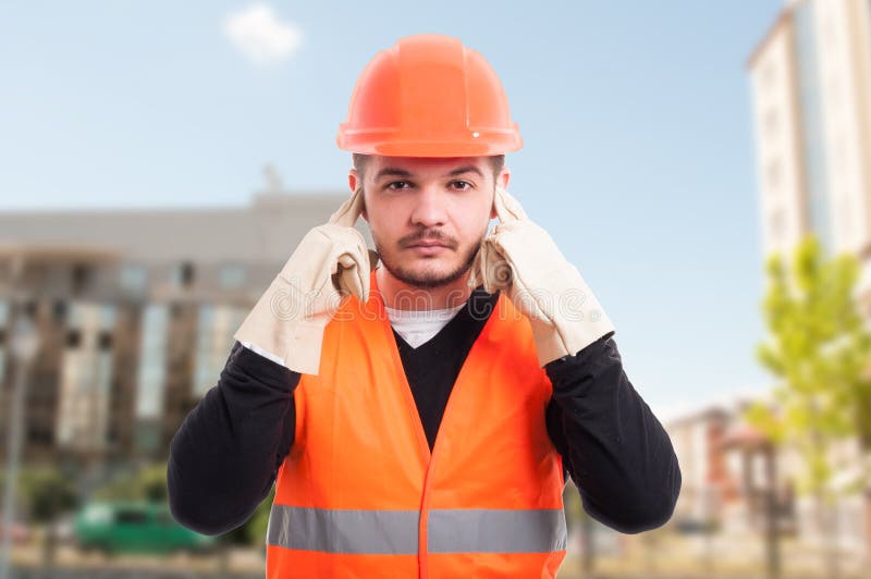 Male constructor doing hear no evil gesture by putting fingers in his ears to not hear a thing. Male constructor doing hear no evil gesture by putting fingers in his ears to not hear a thing
