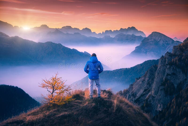 Mann auf der Bergspitze, die auf Gebirgstal schaut