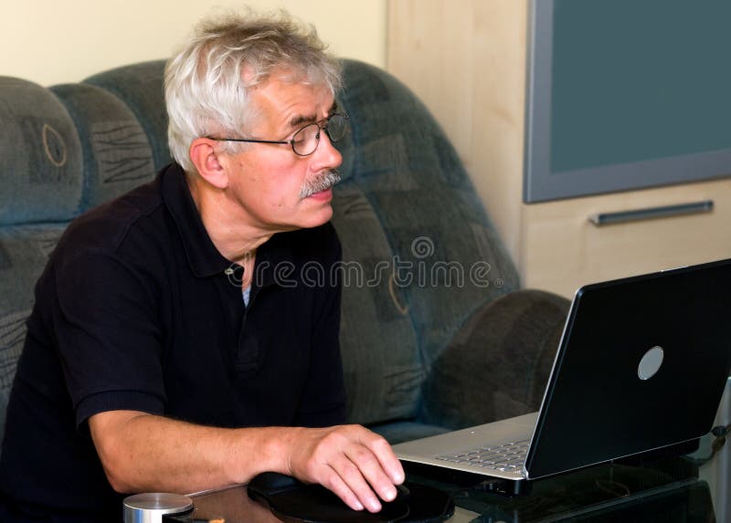 A middle age man sitting on a sofa, looking at a laptop computer monitor. A middle age man sitting on a sofa, looking at a laptop computer monitor.