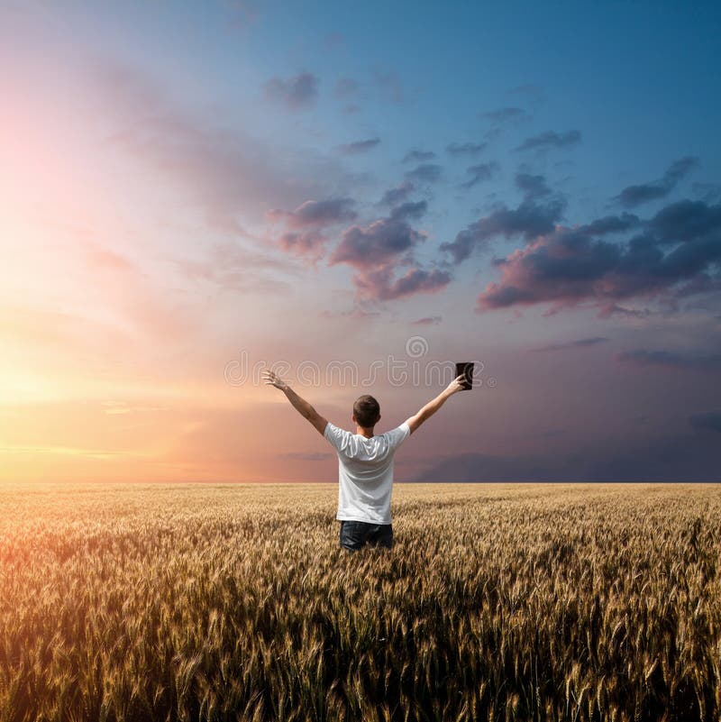 Man holding up Bible in a wheat field with arms up. Man holding up Bible in a wheat field with arms up