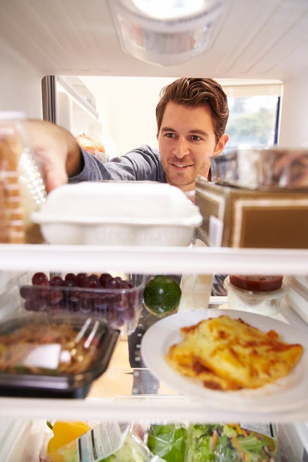 Mann, der den inneren Kühlschrank gefüllt mit Lebensmittel schaut stockfotografie Mann, der den inneren Kühlschrank gefüllt mit Lebensmittel schaut stockfotografie