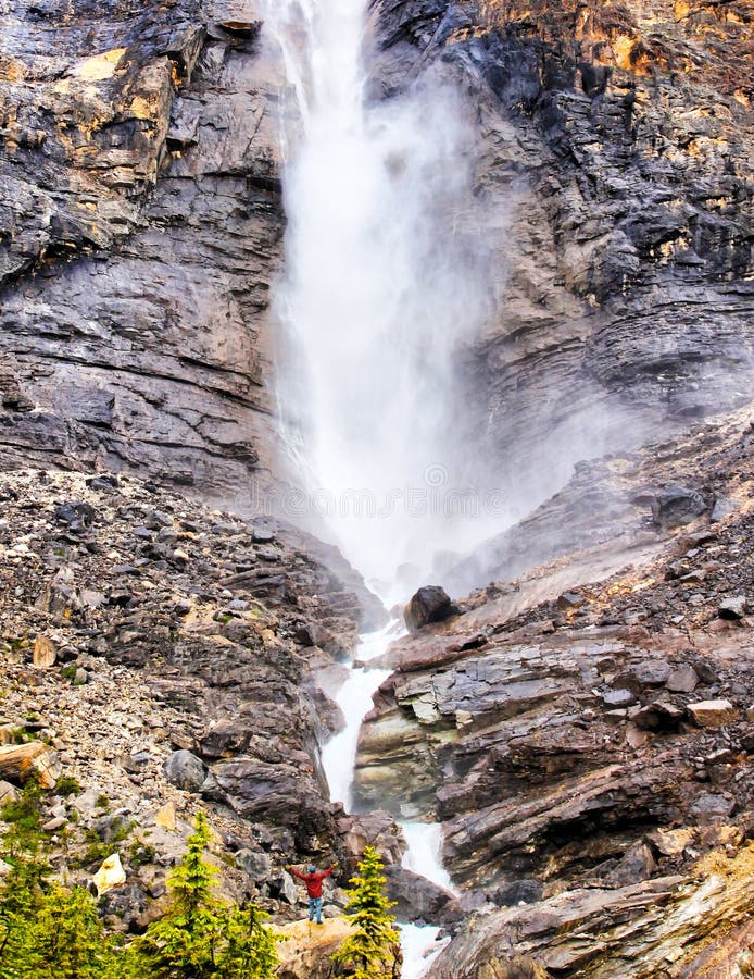 Mann, der in der Ehrfurcht an der Basis des starken Brüllenwasserfalls steht stockfotos Mann, der in der Ehrfurcht an der Basis des starken Brüllenwasserfalls steht stockfotos