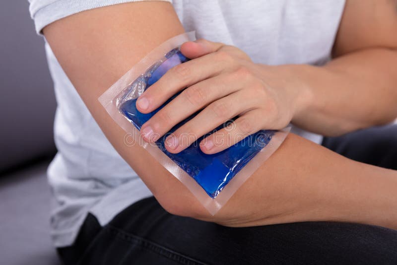 Close-up Of A Man`s Hand Applying Ice Gel Pack On An Injured Elbow. Close-up Of A Man`s Hand Applying Ice Gel Pack On An Injured Elbow