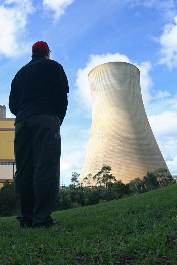 A view of a man looking towards a huge cooling tower of a power generating plant. A view of a man looking towards a huge cooling tower of a power generating plant.