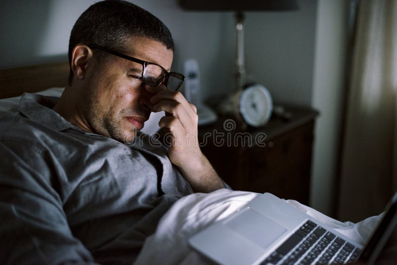 Mann, der Laptop auf einem Bett verwendet stockfotos Mann, der Laptop auf einem Bett verwendet stockfotos
