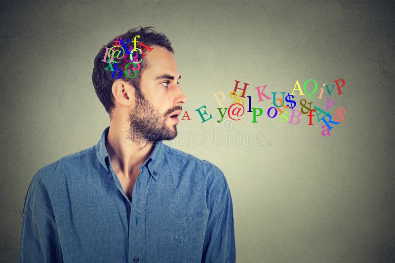 Side view portrait man talking with alphabet letters in his head and coming out of open mouth isolated on gray wall background. Human face expressions, emotions. Communication, intelligence concept. Side view portrait man talking with alphabet letters in his head and coming out of open mouth isolated on gray wall background. Human face expressions, emotions. Communication, intelligence concept