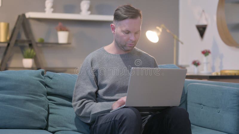 Mann, der mit Laptop zu Hause sitzt lizenzfreies stockbild