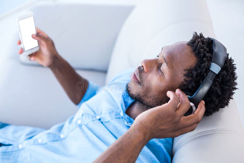 Man enjoying music while relaxing on sofa at home. Man enjoying music while relaxing on sofa at home