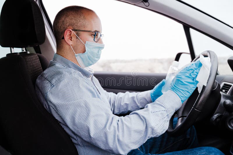 Mann in einem Auto mithilfe des Alkoholgels des Lenkrads während des Pandemie Coronavirus covid19 zu desinfizierendem