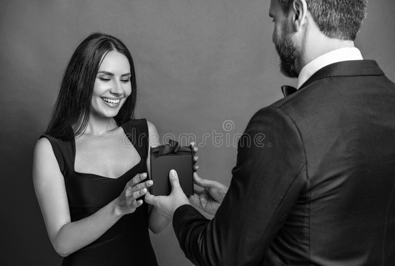 Mann geben Geschenkbox Valentinstag an Frau. Happy Valentines Day. Paar verliebt isoliert auf rot. lizenzfreie stockfotografie