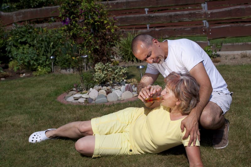Mann gibt Frau mit Hitzeschaden etwas zu trinken lizenzfreies stockfoto Mann gibt Frau mit Hitzeschaden etwas zu trinken lizenzfreies stockfoto