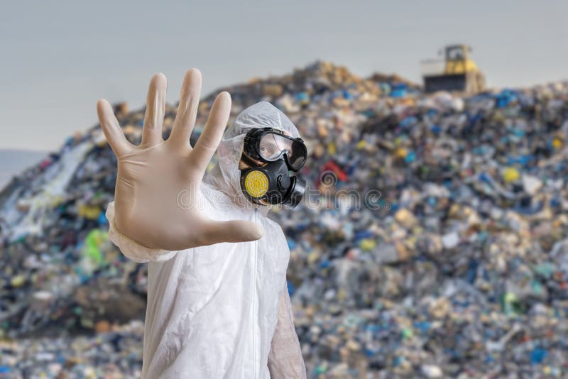 Man in coveralls is showing stop gesture. Garbage pile in landfill in background. Man in coveralls is showing stop gesture. Garbage pile in landfill in background.