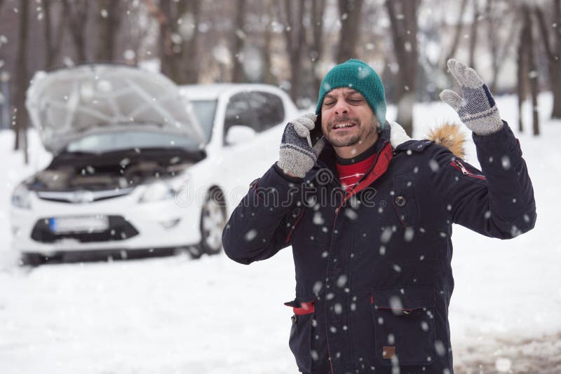 Young man in snow, he is under stress because his broken down car. Young man in snow, he is under stress because his broken down car.