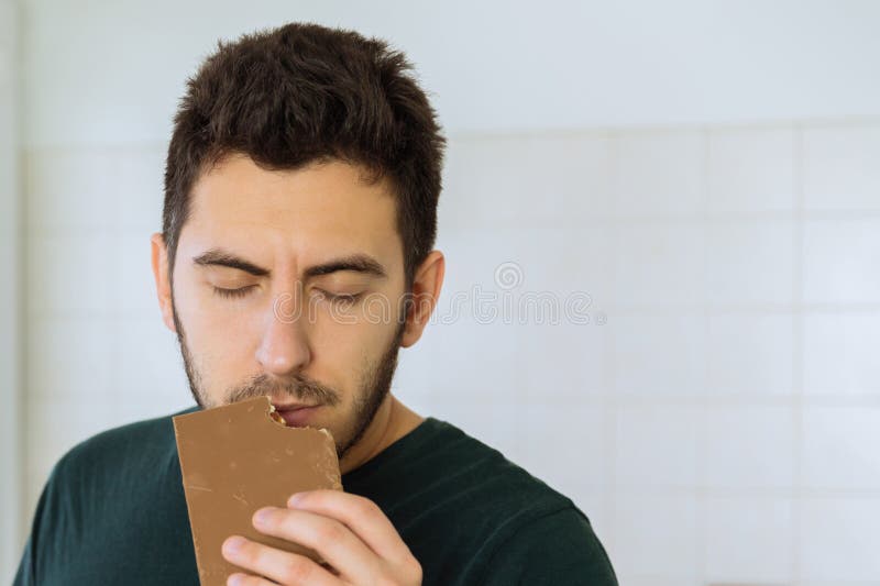 Mann isst Schokolade mit großem Vergnügen Begriffsfoto über Bonbons lizenzfreies stockfoto Mann isst Schokolade mit großem Vergnügen Begriffsfoto über Bonbons lizenzfreies stockfoto
