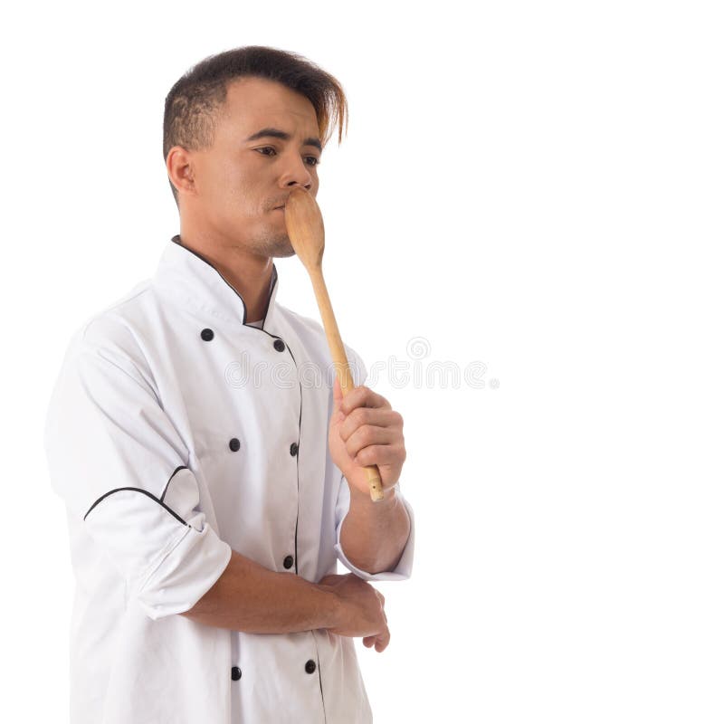 Mann ist nachdenklich Junger schwarzer Mann ist in der weißen Kochuniform. Mann hält Arbeitsinstrument und ist durchdacht Junger Chef ist in der Uniform Weißer Hintergrund