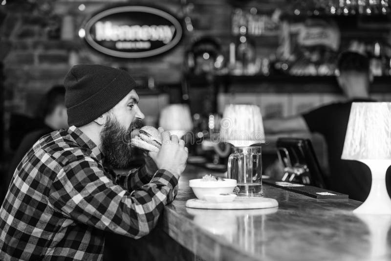 Mann mit Bart essen Burgermen? B?rtiger Mann des groben Hippies sitzen am Stangenz?hler Hohes Kalorien-Lebensmittel Betr?germahlz lizenzfreie stockfotos Mann mit Bart essen Burgermen? B?rtiger Mann des groben Hippies sitzen am Stangenz?hler Hohes Kalorien-Lebensmittel Betr?germahlz lizenzfreie stockfotos
