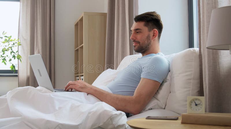 Mann mit Laptop im Bett zu Hause Schlafzimmer